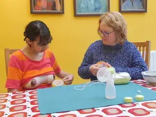 Old woman teaching young woman to pump breast milk